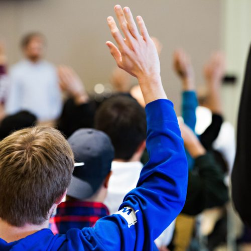 students raising hand in class